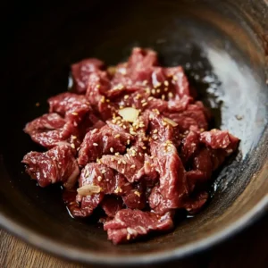 A plate of sizzling Garlic Pepper Beef with tender strips of beef in a rich, savory garlic and black pepper sauce, garnished with fresh herbs.